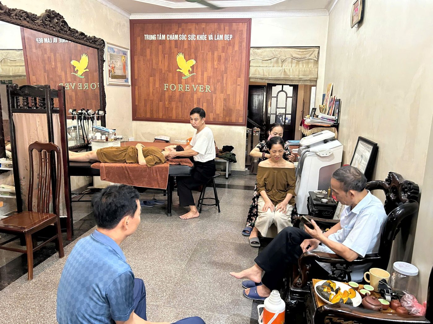 Khu vực tiếp đón với khách hàng đang chờ và bàn trị liệu bên trong