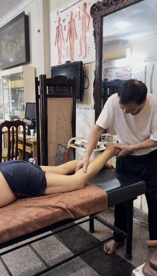 Lương y trị liệu vùng chân cho khách hàng nằm trên bàn